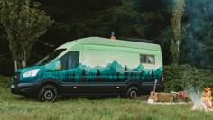 a camper van parked next to a fire pit in the middle of a field