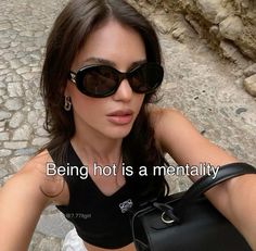 a woman wearing sunglasses and holding a black purse with the words being not is a mentality