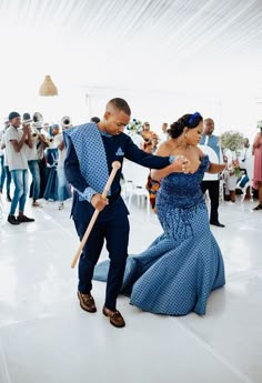 a man and woman dancing on a dance floor with people in the background holding umbrellas