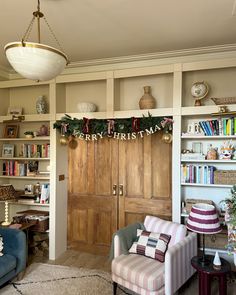 a living room filled with furniture and bookshelves next to a christmas wreath on the wall