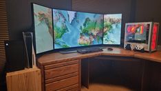 three computer monitors sitting on top of a wooden desk