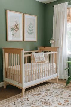 a baby's crib in a green room with two pictures on the wall