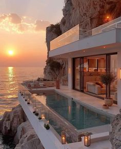 an ocean front house with a pool and sunset in the background