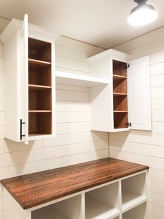 an empty room with white cabinets and wooden shelves