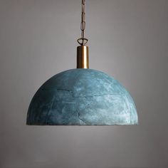 a blue pendant light hanging from a metal chain on a gray wall with a white background