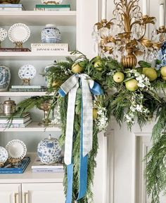 a christmas wreath on top of a mantle with blue and white plates in the background