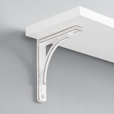 a close up of a white shelf on a wall with a metal hook attached to it