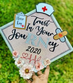 someone is holding up a graduation cap that says trust in your rny with flowers and a stethoscope on it