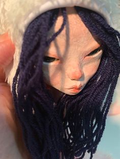 a close up of a doll wearing a hat with long purple dreadlocks on it's head