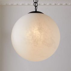 a light fixture hanging from the ceiling in a room with white walls and flooring