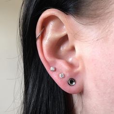 a close up of a person's ear with three piercings