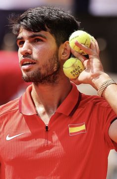 a man holding two tennis balls up to his face