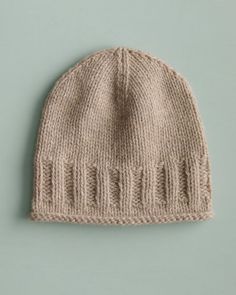 a beige knitted hat on a green background with copy space for the wording