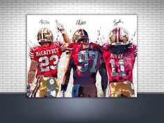 three football players are standing in front of a white brick wall with their hands up