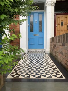 a black and white checkered floor in front of a blue door on a brick building