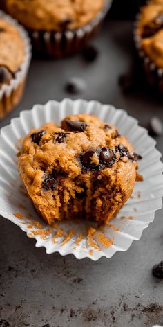 chocolate chip muffins sitting on top of white paper cupcake liners next to other muffins