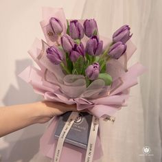 a bouquet of purple tulips is being held by a woman's hand