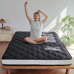 a woman sitting on top of a bed with her arms in the air and smiling