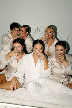 a group of women sitting on top of a bed holding champagne flutes in their hands