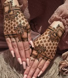 two hands with henna designs on them, one is holding the other's hand