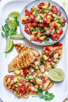 grilled chicken with pineapple salsa and lime wedges on a white platter