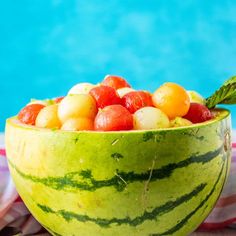 a watermelon bowl filled with fruit next to a swimming pool