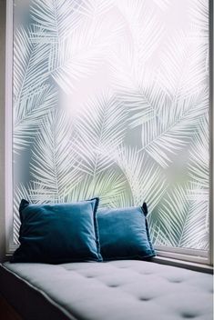 a bed sitting in front of a window with palm leaves on it