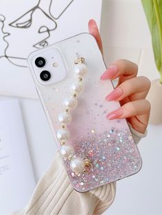 a woman holding up her phone case with pearls on it