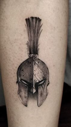 a black and white photo of a spartan's helmet tattoo on the right thigh