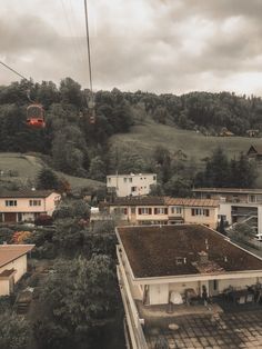 an overhead view of houses and trees on a cloudy day with a cable car in the background