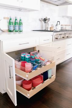 an open cabinet in a kitchen filled with dishes and cups on the bottom shelf is full of cleaning supplies