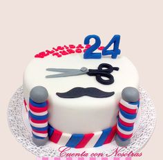 a white cake with red, blue and grey stripes on it that has a pair of scissors sitting on top of the cake