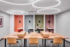 a person sitting at a long table in an office with pink and orange accents on the walls