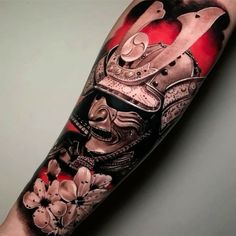 a man's arm with a japanese mask and flowers on it