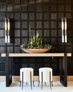 a table with two stools and a bowl on it in front of a wall