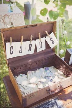 an open suitcase sitting on top of a wooden table filled with cards and other items