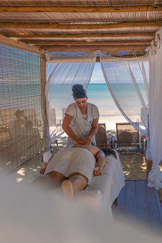 a woman sitting on top of a bed next to the ocean