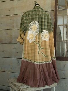 an old fashioned shirt with flowers on it is sitting on a bench in front of a wooden wall