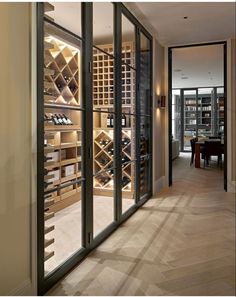 a wine cellar in the middle of a room with glass doors leading to another room