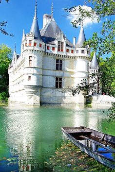 an old castle sitting on top of a lake next to a boat in the water