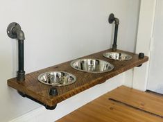 two metal bowls sitting on top of a wooden shelf