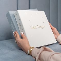 a woman is holding a box with the word lusta taylor written on it while sitting on a couch