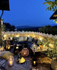 an outdoor seating area is lit up with candles