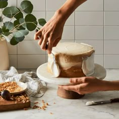 a person is decorating a cake with icing and walnuts on a plate