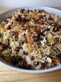 a bowl filled with rice and nuts on top of a wooden table