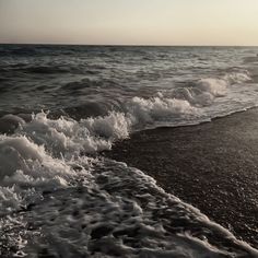 the sun is shining over the water and waves on the sand at the ocean's edge