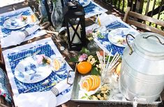 an outdoor table set with blue and white dishes