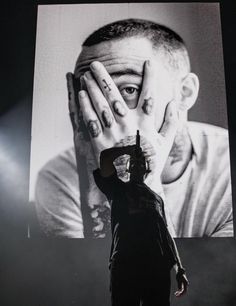 a man holding his hands to his face while standing in front of a large screen