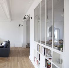 a living room filled with furniture next to a white book shelf on top of a hard wood floor