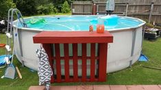 an above ground pool with a red table next to it and other items on the lawn